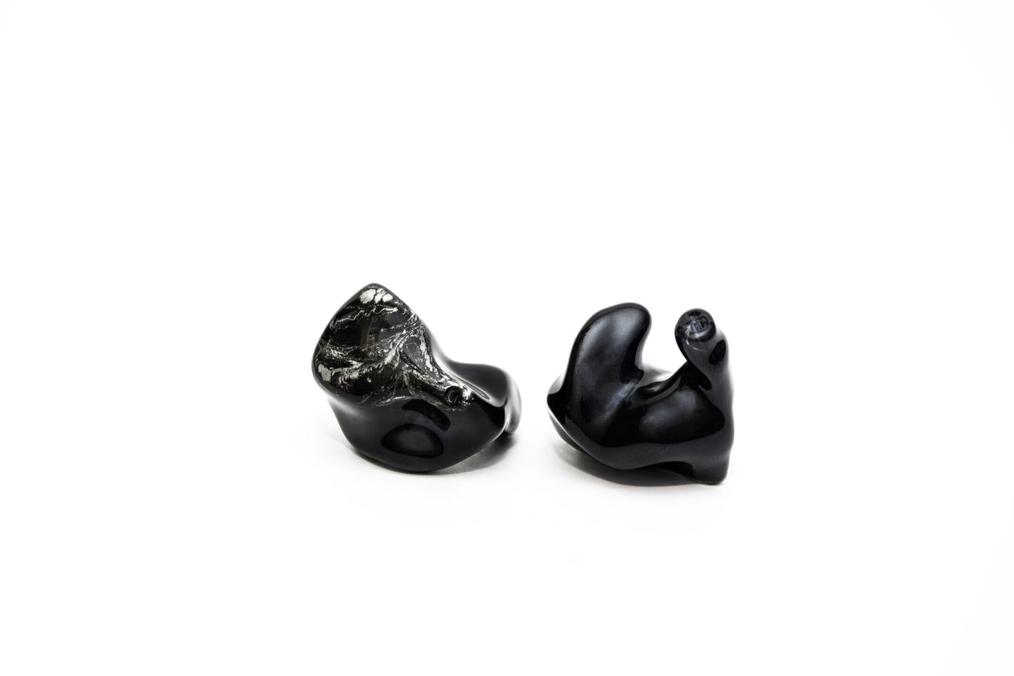 A pair of black custom in-ear monitors with a distinctive design, featuring a black and silver color scheme and a metallic finish. Right in-ear monitor
is flipped to show contours.