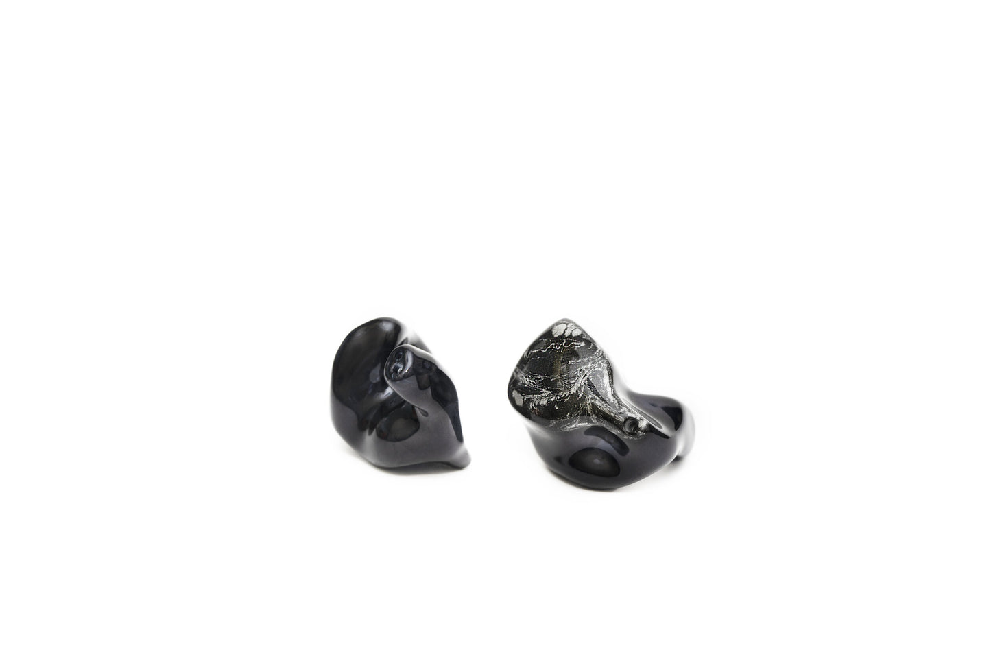 A pair of black custom in-ear monitors with a distinctive design, featuring a black and silver color scheme and a metallic finish. Left in-ear monitor is flipped to show the contours.