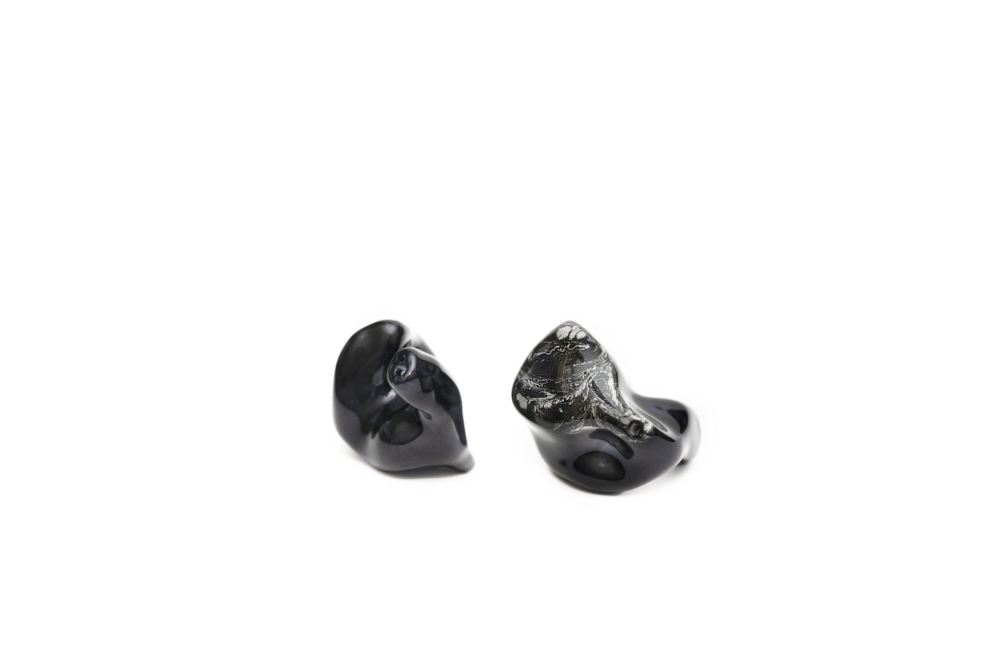 A pair of black custom in-ear monitors with a distinctive design, featuring a black and silver color scheme and a metallic finish. Left in-ear monitor is flipped to show the contours.